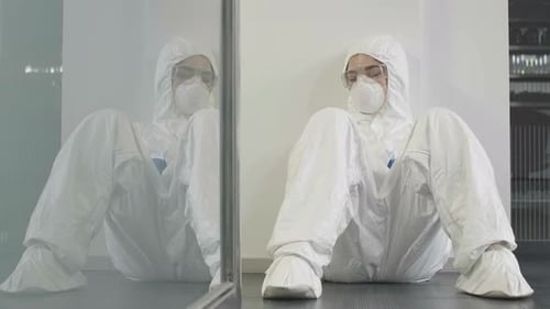 Femme épuisée portant une combinaison antivirale et un respirateur dormant au gymnase ou au bureau après la désinfection