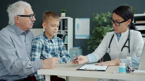 Female Doctor Talking To Grandfather and Grandson in Office Discussing Child's Health