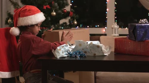 Excited Boy Opening Christmas Present at Home