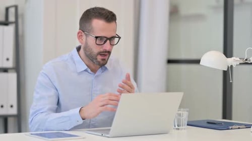 Excited Man Celebrates Good News on Laptop in Office