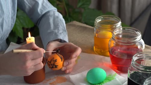 Hands Decorate Easter Egg with Candle Wax