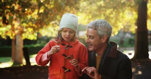 Father and Daughter Play with Bubbles in Park