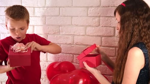 Boy and Girl Open Birthday Gifts Near Balloons
