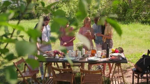 Friends Gather Around Table for Outdoor Picnic