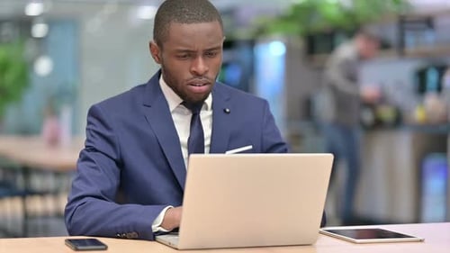 Sick African Businessman with Laptop Coughing in Office