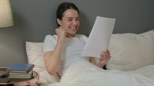 Young Woman Excited by Letter While in Bed