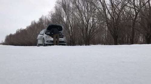Man Repairing Car on Snowy Winter Road