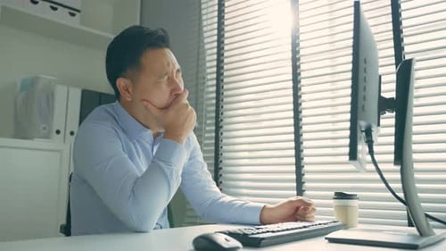 Exhausted Asain business man using laptop computer working in office.