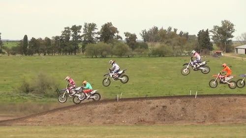 Motocross Riders Jumping Over Dirt Track Hill