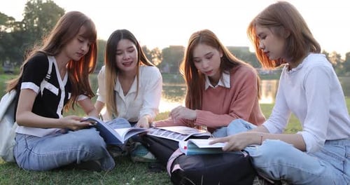 Grupo de amigas estudantes universitárias asiáticas estão sentadas juntas no parque.