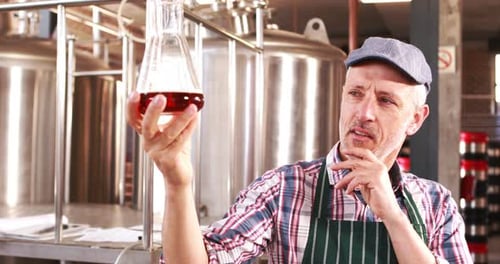 Man Examining and Approving Beer Sample in Brewery