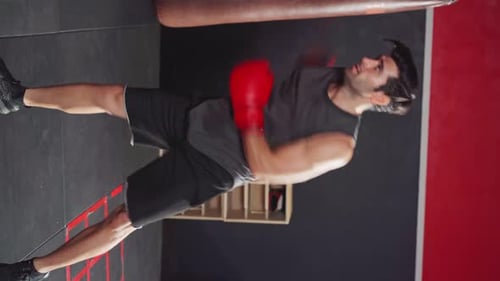Man Powerfully Boxing a Punching Bag at the Gym