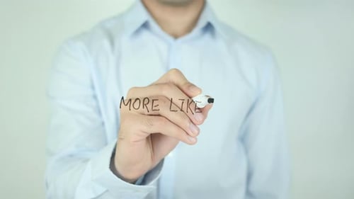 Man Writing More Likes on a Clear Screen