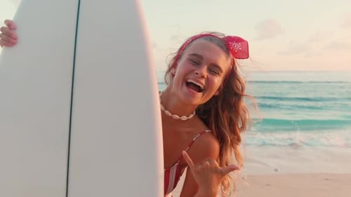 Smiling Woman Holding Surfboard on Beach at Sunset
