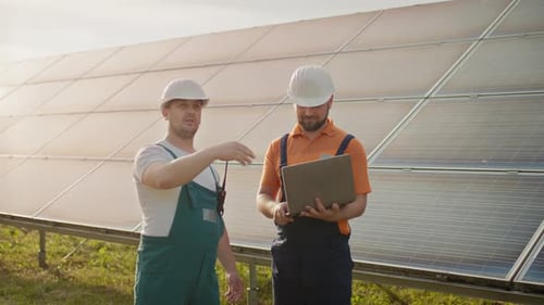 Männliche Ingenieure stehen auf Solarpark und diskutieren über effizienten Plan von