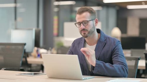 Middle Aged Businessman Talking on Video Call on Laptop in Office