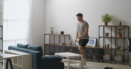 Attractive Young Man Is Doing Workout in Living Room at Morning Doing Exercise for Legs Muscles with