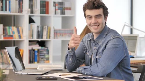 Man Giving Thumbs Up at Desk in Office
