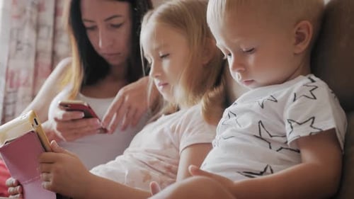 Mother and Children Use Technology Together on Couch
