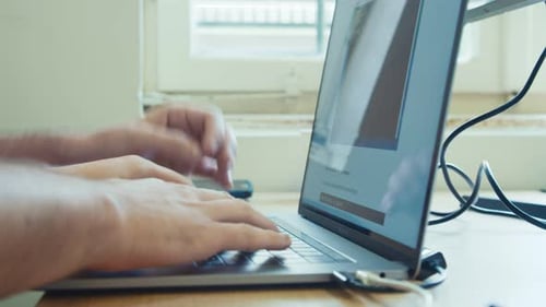 Man hands typing on a laptop computer keyboard