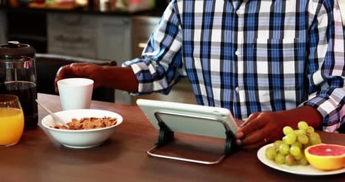 Senior Man Using Tablet at Breakfast Table