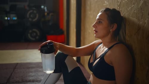 Fitness Woman Drinking Water From Bottle. Muscular Young Female at Gym Taking a Break From Workout.