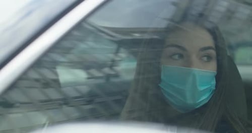 Woman Wearing Mask Covers Face in Car