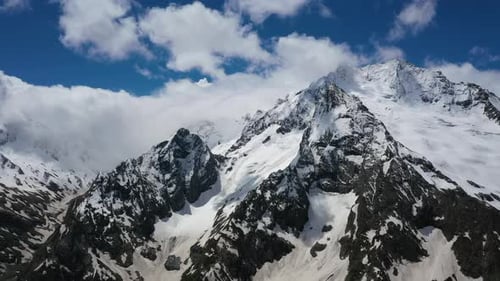 Air Flight Through Mountain Clouds Over Beautiful Snowcapped Peaks of Mountains and Glaciers