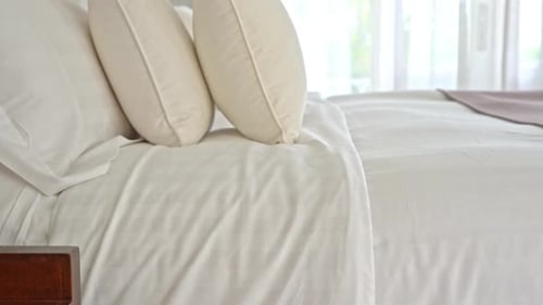 Clean White Bed with Pillows and White Sheets