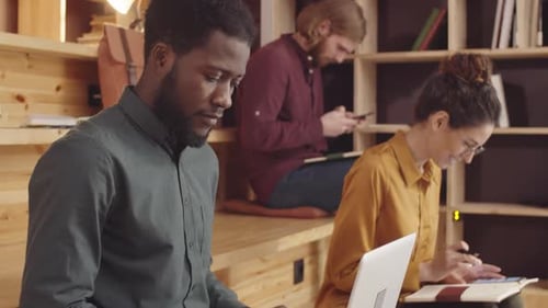 Trois jeunes hipsters travaillant sur un ordinateur portable et un smartphone dans un café