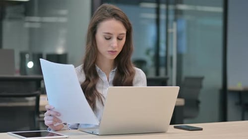 Woman Working With Laptop And Documents In Office