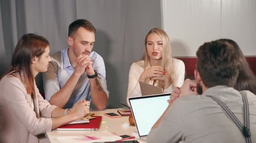Frau spricht in Gesellschaft ihrer Kollegen über eine Idee bei einem Treffen im Büro