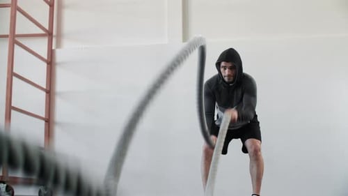 Handsome Muscular Man Training Rope Exercise During Intensive Workout in Gym