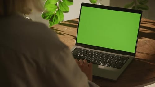 Handheld Shot of a Woman Single Scroll on a Laptop Computer with Green Screen Chroma Key Indoors