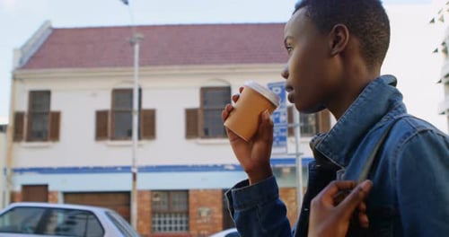 Woman having coffee while walking in city street 4k