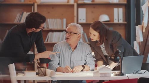 Team of Mixed-Aged Architects Discussing Construction Plan in Office