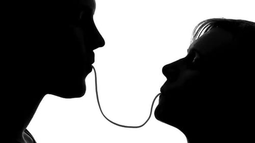 Silhouettes of Woman and Man Eating Spaghetti and Kissing Tenderly on Date
