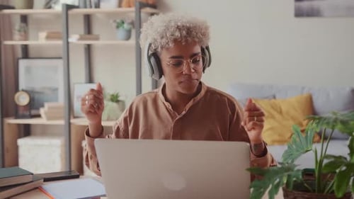 Enthusiastic Woman Dancing with Headphones and Laptop