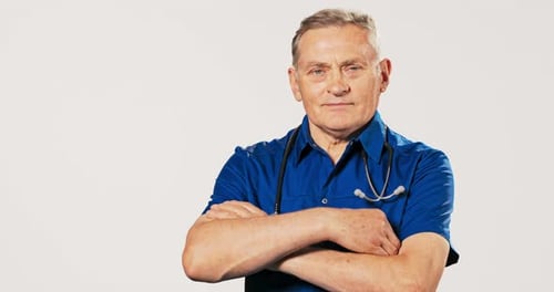 Mature Doctor Poses with Stethoscope Against White Background