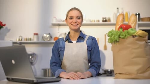 Smiling Woman in Kitchen with Bag of Groceries