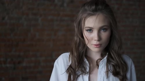 Portrait of an Attractive Girl in a White Blouse Close-up. Beautiful Blue-eyed Model Looking Into