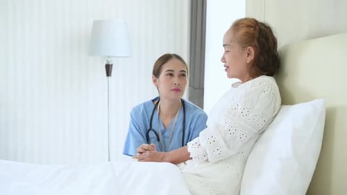 The doctor is talking to an elderly patient who is alone in a special hospital room.