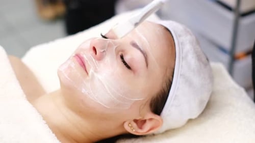 Woman Receiving Facial Cream Treatment at Spa