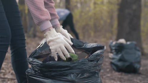Mujer poniendo botellas de plástico en una bolsa