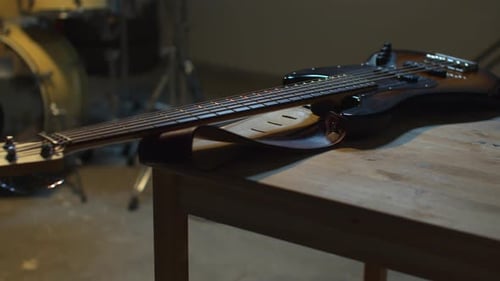 Bass Guitar on Wooden Table with Drum Kit