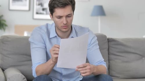 Man Looking at Document Reacts with Stress
