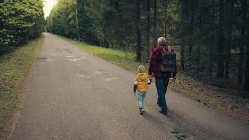 Old Man with Backpack and Fishing Road is Walking and Holding Hand of His Little Grandson