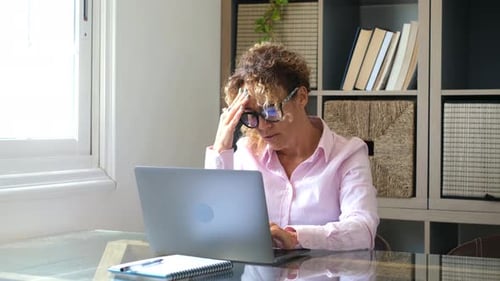Woman working at computer laptop at home with headache - stress and tired people