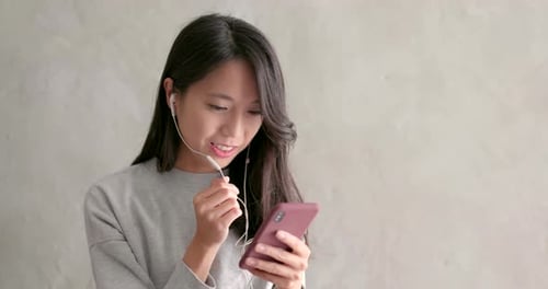 Young Woman Talking into Smartphone Earphones Indoors