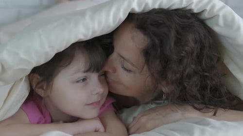 Woman and Child Cuddling Together in Bed